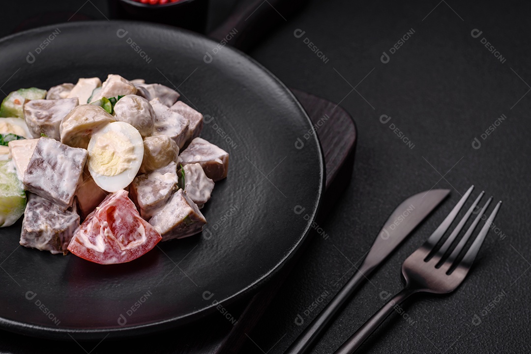 Deliciosa salada com língua de boi cozida, ovos de codorna, tomate e pepino sobre um fundo escuro de concreto