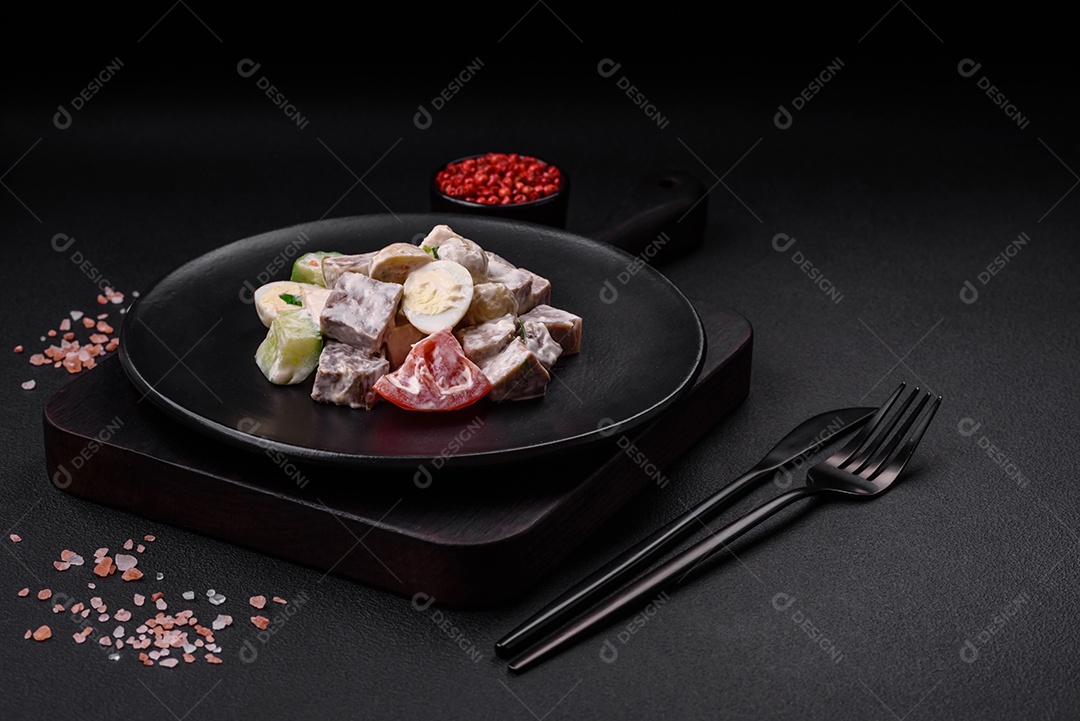 Deliciosa salada com língua de boi cozida, ovos de codorna, tomate e pepino sobre um fundo escuro de concreto