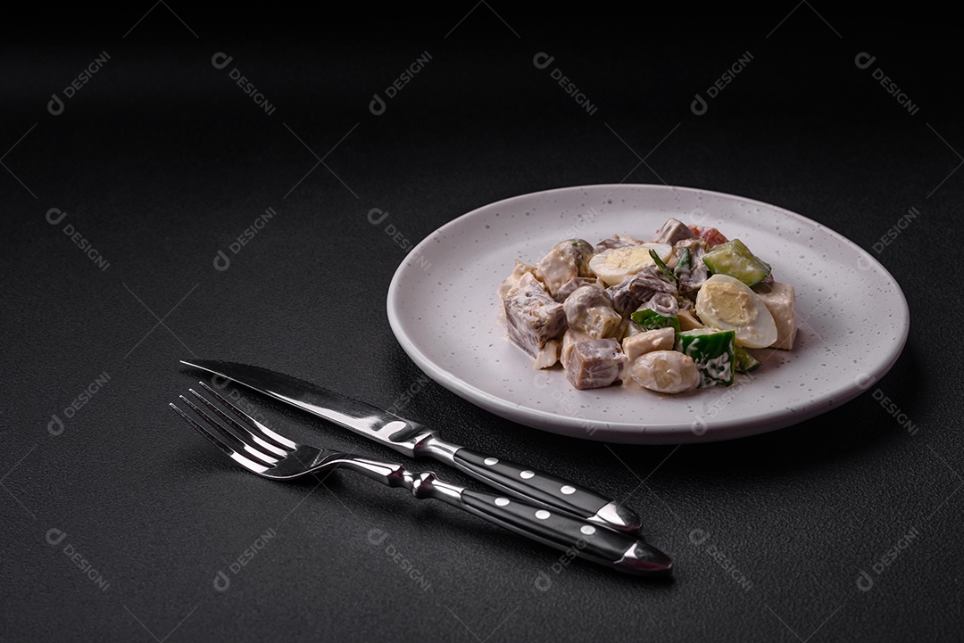 Deliciosa salada com língua de boi cozida, ovos de codorna, tomate e pepino sobre um fundo escuro de concreto