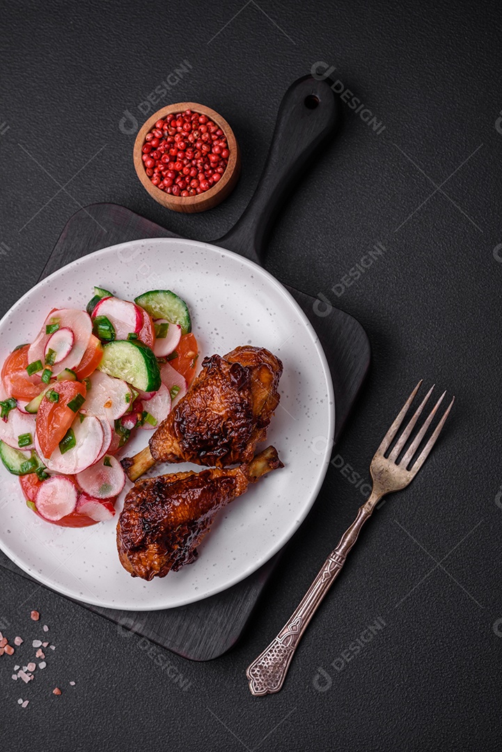 Deliciosa salada vegana de legumes frescos de tomate, pepino e rabanete com sal e especiarias sobre um fundo escuro de concreto