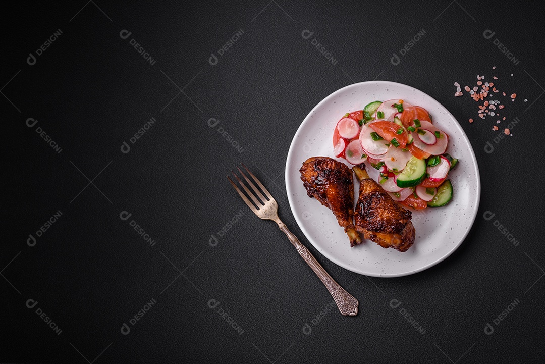 Deliciosa salada vegana de legumes frescos de tomate, pepino e rabanete com sal e especiarias sobre um fundo escuro de concreto