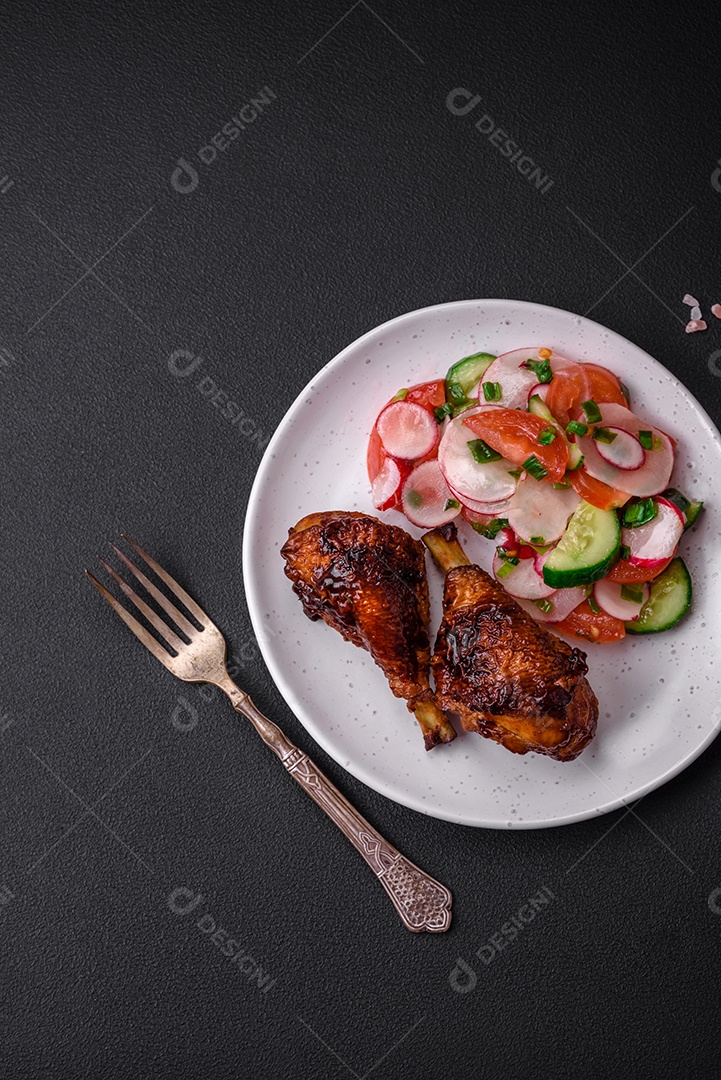 Deliciosa salada vegana de legumes frescos de tomate, pepino e rabanete com sal e especiarias sobre um fundo escuro de concreto