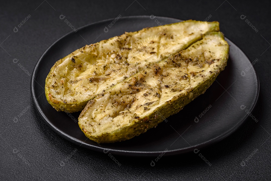 Deliciosa abobrinha cortada em duas metades assada com sal, especiarias e ervas sobre um fundo escuro de concreto