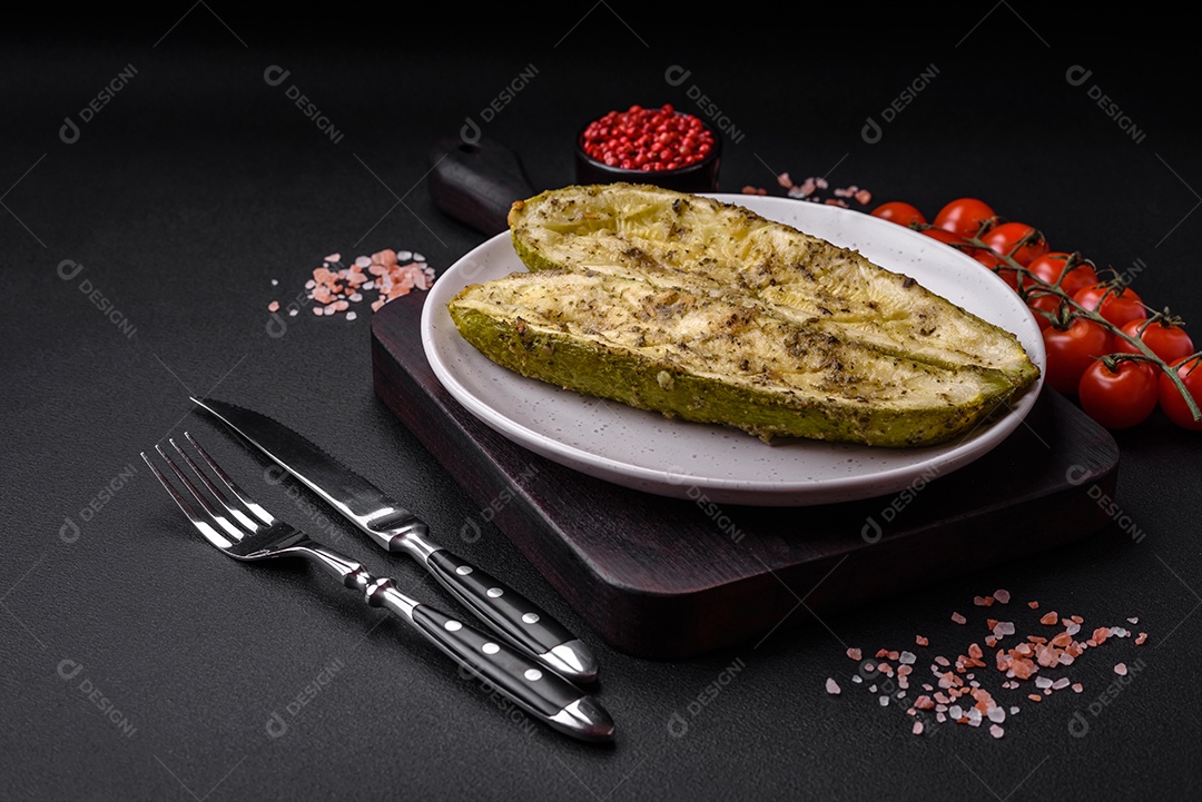 Deliciosa abobrinha cortada em duas metades assada com sal, especiarias e ervas sobre um fundo escuro de concreto