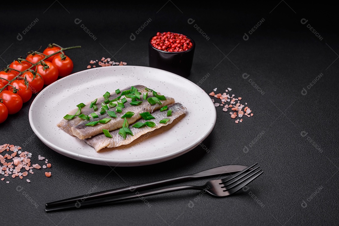 Delicioso arenque do Atlântico marinado com sal e especiarias em óleo sobre um fundo escuro de concreto