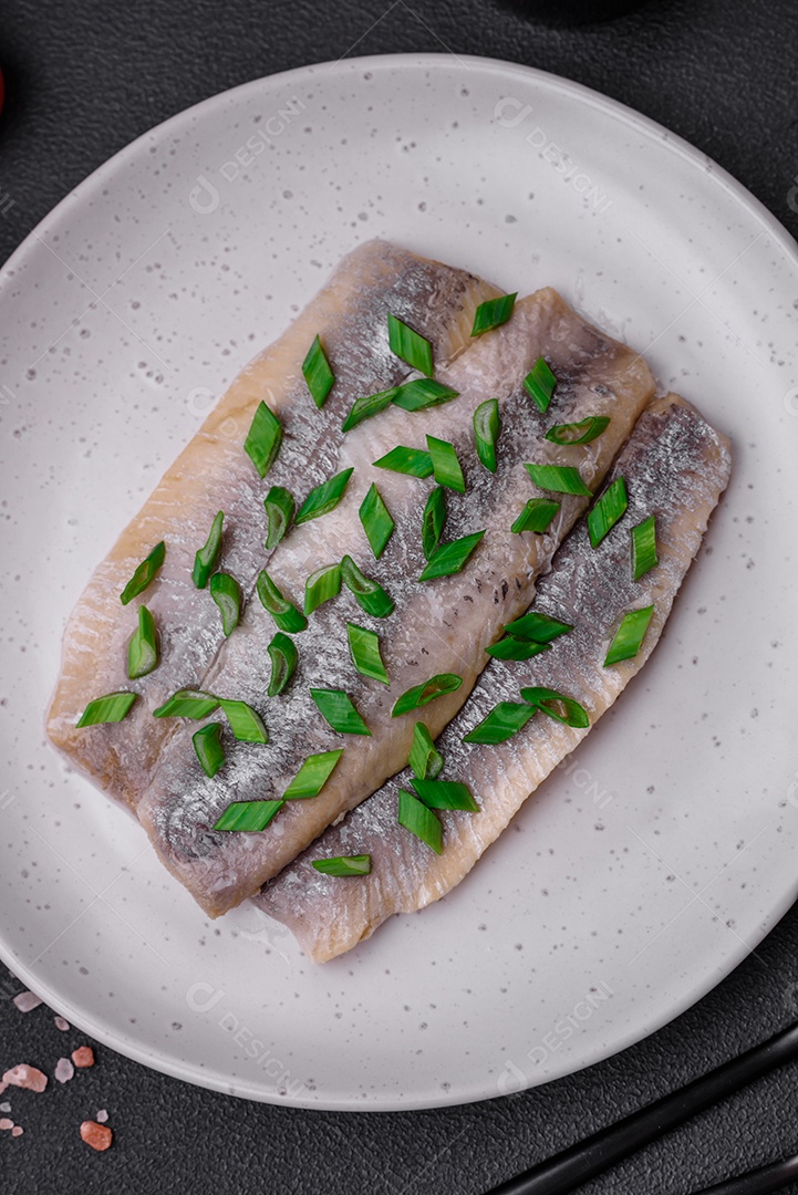 Delicioso arenque do Atlântico marinado com sal e especiarias em óleo sobre um fundo escuro de concreto