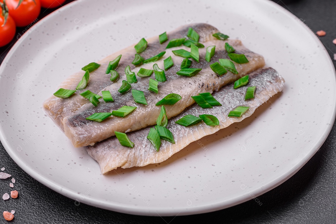 Delicioso arenque do Atlântico marinado com sal e especiarias em óleo sobre um fundo escuro de concreto