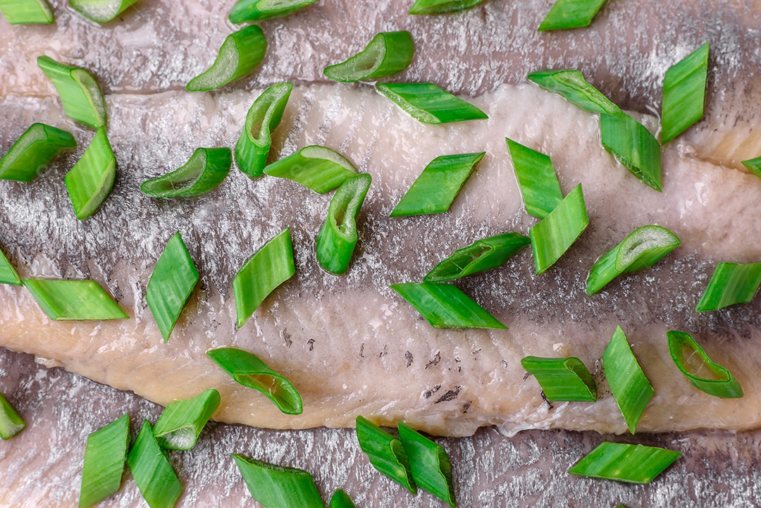 Delicioso arenque do Atlântico marinado com sal e especiarias em óleo sobre um fundo escuro de concreto