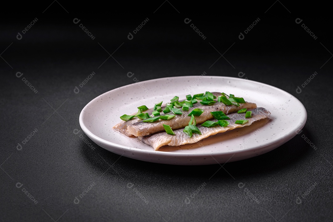 Delicioso arenque do Atlântico marinado com sal e especiarias em óleo sobre um fundo escuro de concreto
