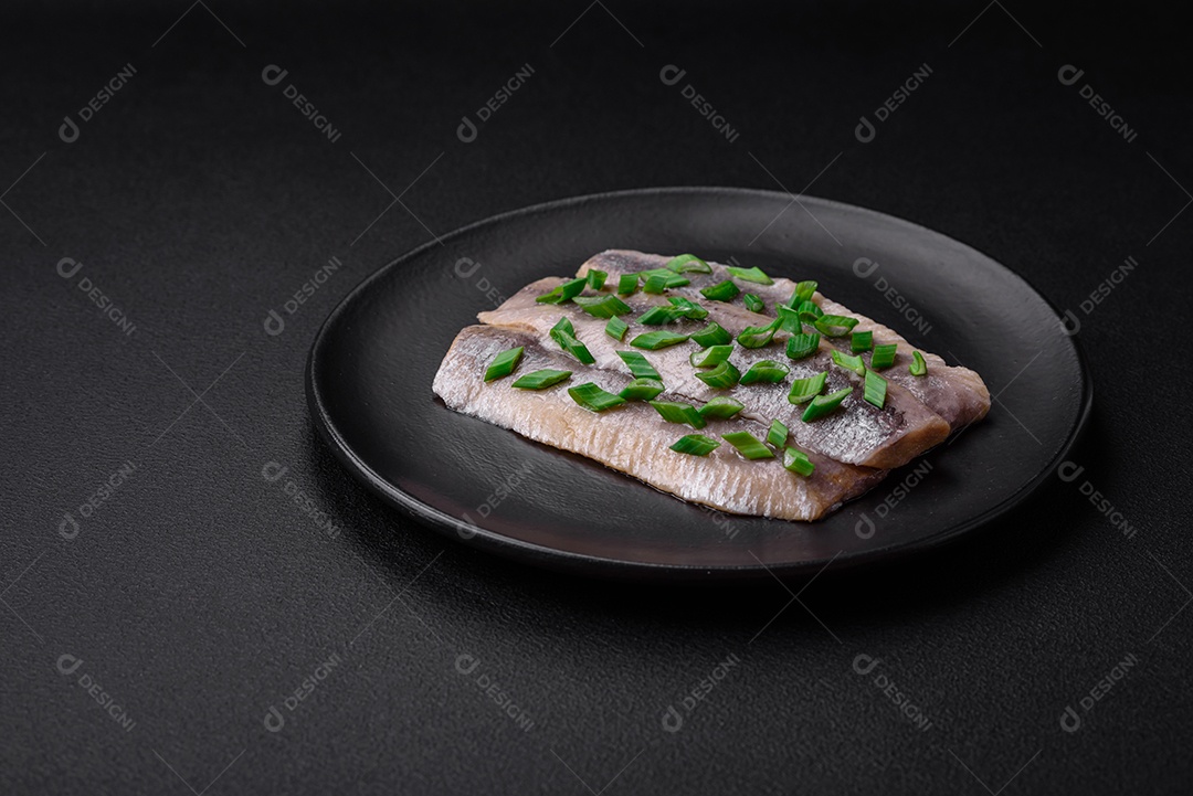 Delicioso arenque do Atlântico marinado com sal e especiarias em óleo sobre um fundo escuro de concreto