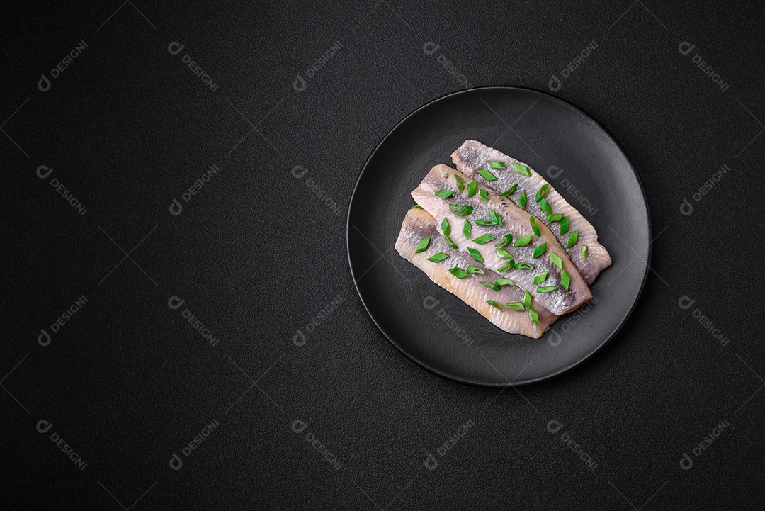 Delicioso arenque do Atlântico marinado com sal e especiarias em óleo sobre um fundo escuro de concreto