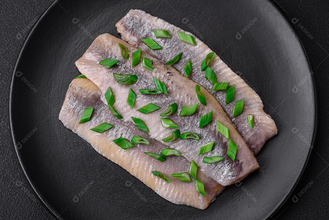 Delicioso arenque do Atlântico marinado com sal e especiarias em óleo sobre um fundo escuro de concreto