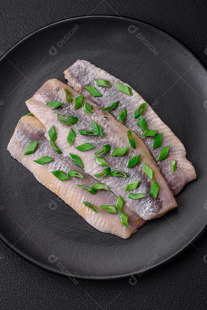 Delicioso arenque do Atlântico marinado com sal e especiarias em óleo sobre um fundo escuro de concreto