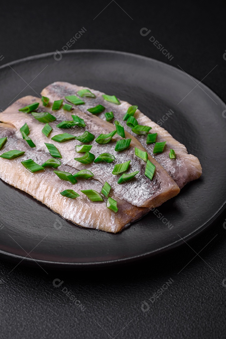 Delicioso arenque do Atlântico marinado com sal e especiarias em óleo sobre um fundo escuro de concreto