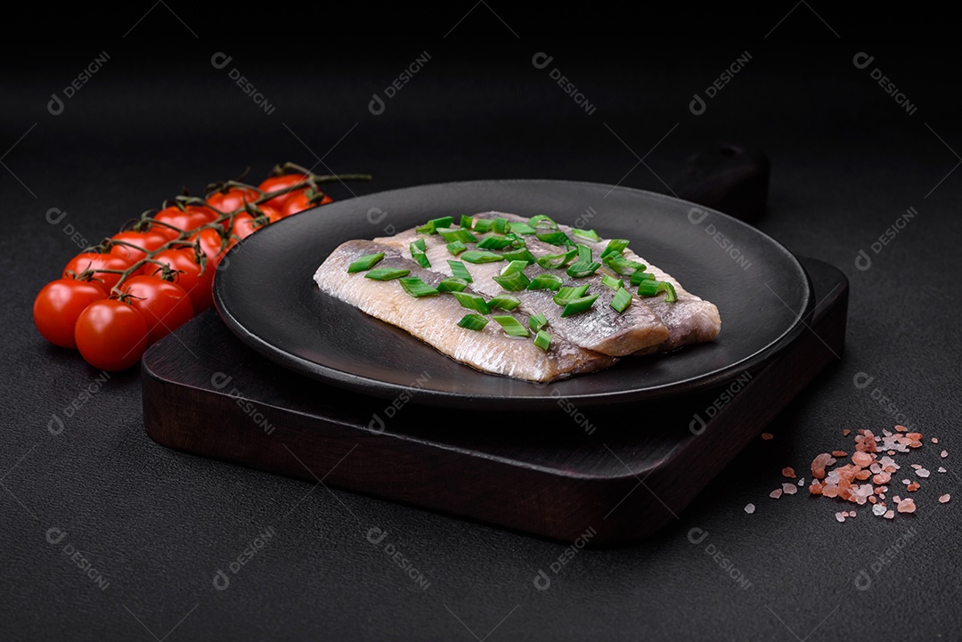 Delicioso arenque do Atlântico marinado com sal e especiarias em óleo sobre um fundo escuro de concreto