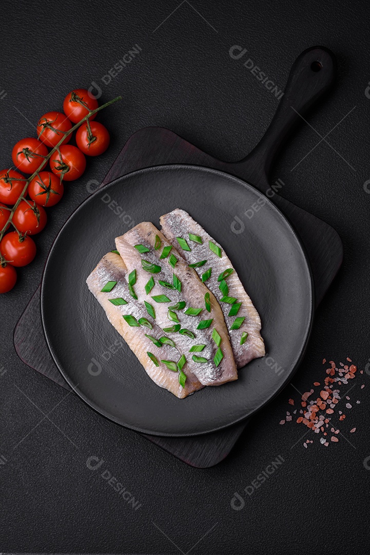 Delicioso arenque do Atlântico marinado com sal e especiarias em óleo sobre um fundo escuro de concreto