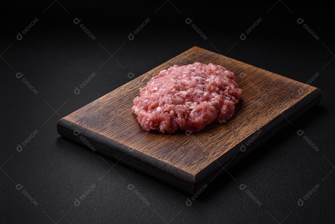 Carne picada crua, carne de porco ou frango com sal, especiarias e ervas sobre um fundo escuro de concreto