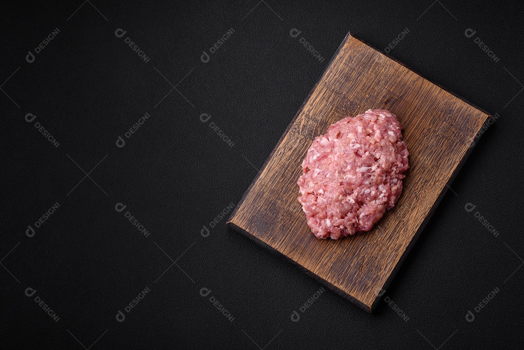 Carne picada crua, carne de porco ou frango com sal, especiarias e ervas sobre um fundo escuro de concreto