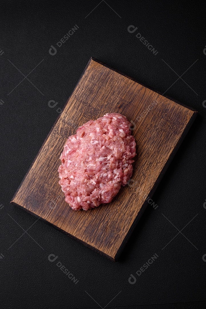 Carne picada crua, carne de porco ou frango com sal, especiarias e ervas sobre um fundo escuro de concreto