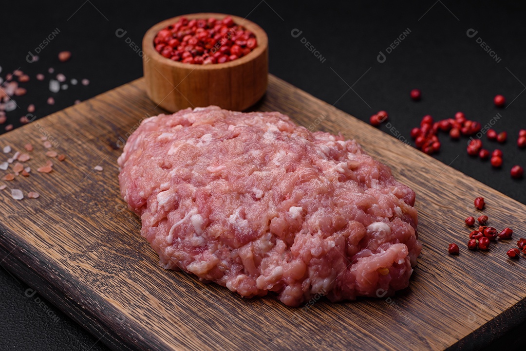 Almôndegas cruas de carne picada, carne de porco ou frango com sal, especiarias e ervas sobre um fundo escuro de concreto