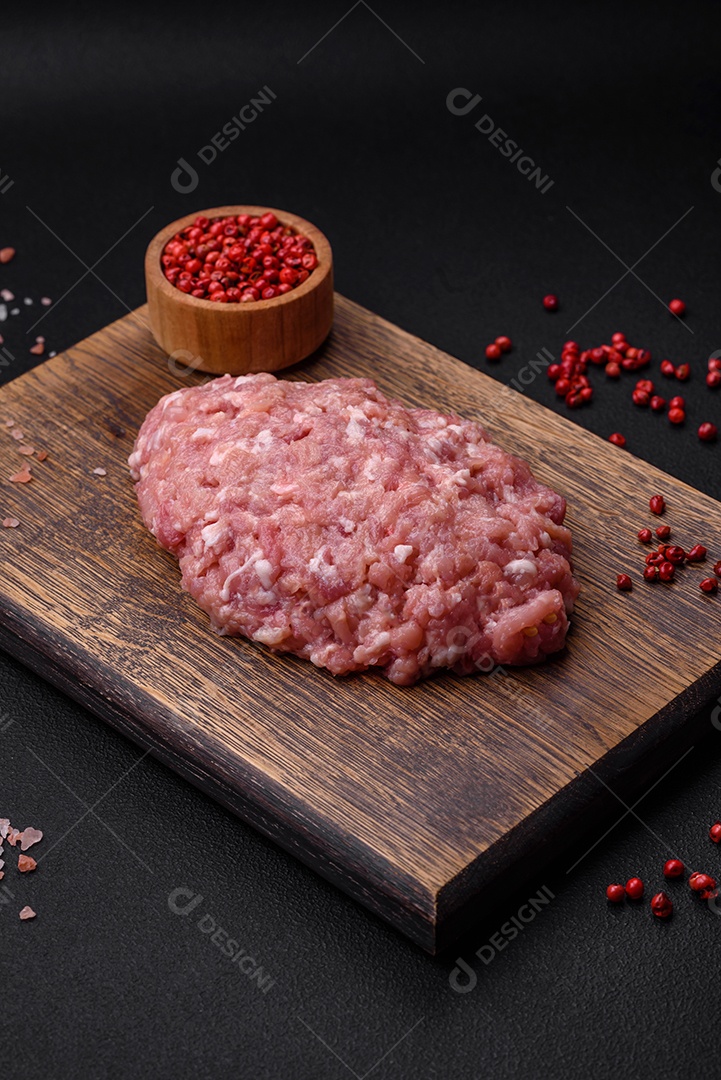 Almôndegas cruas de carne picada, carne de porco ou frango com sal, especiarias e ervas sobre um fundo escuro de concreto