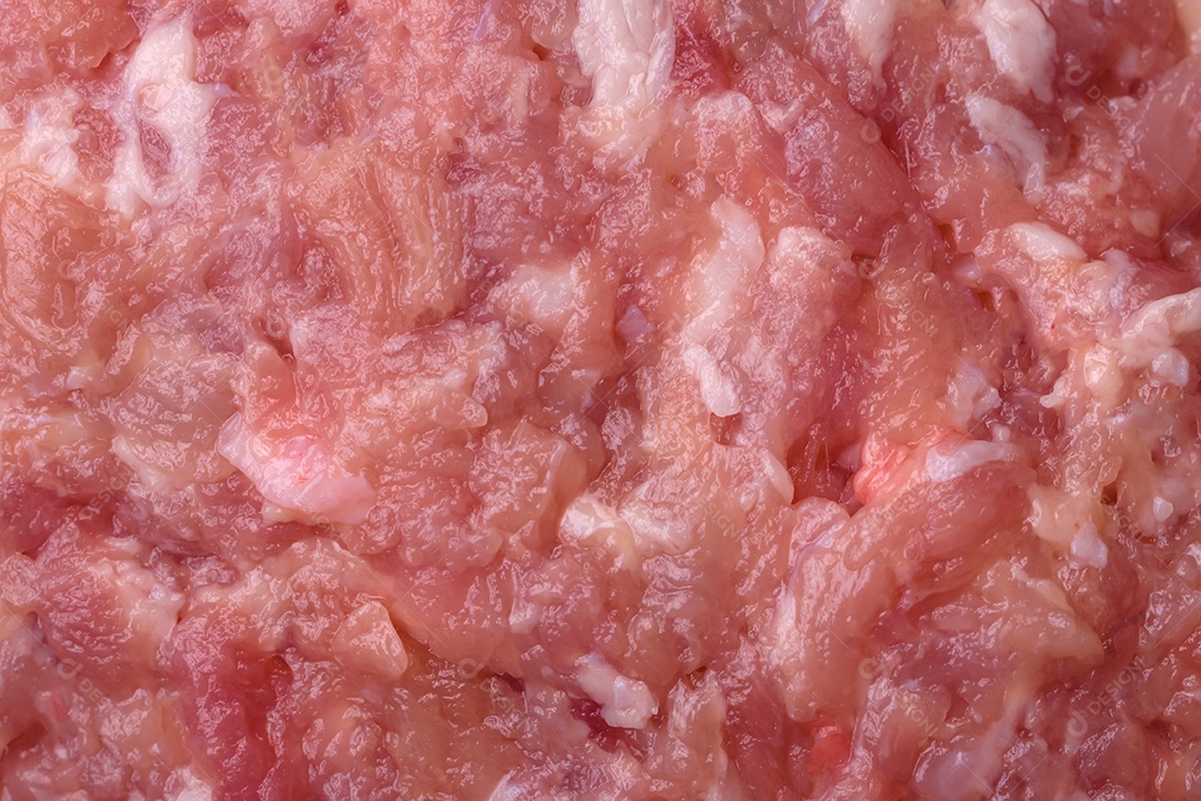 Almôndegas cruas de carne picada, carne de porco ou frango com sal, especiarias e ervas sobre um fundo escuro de concreto