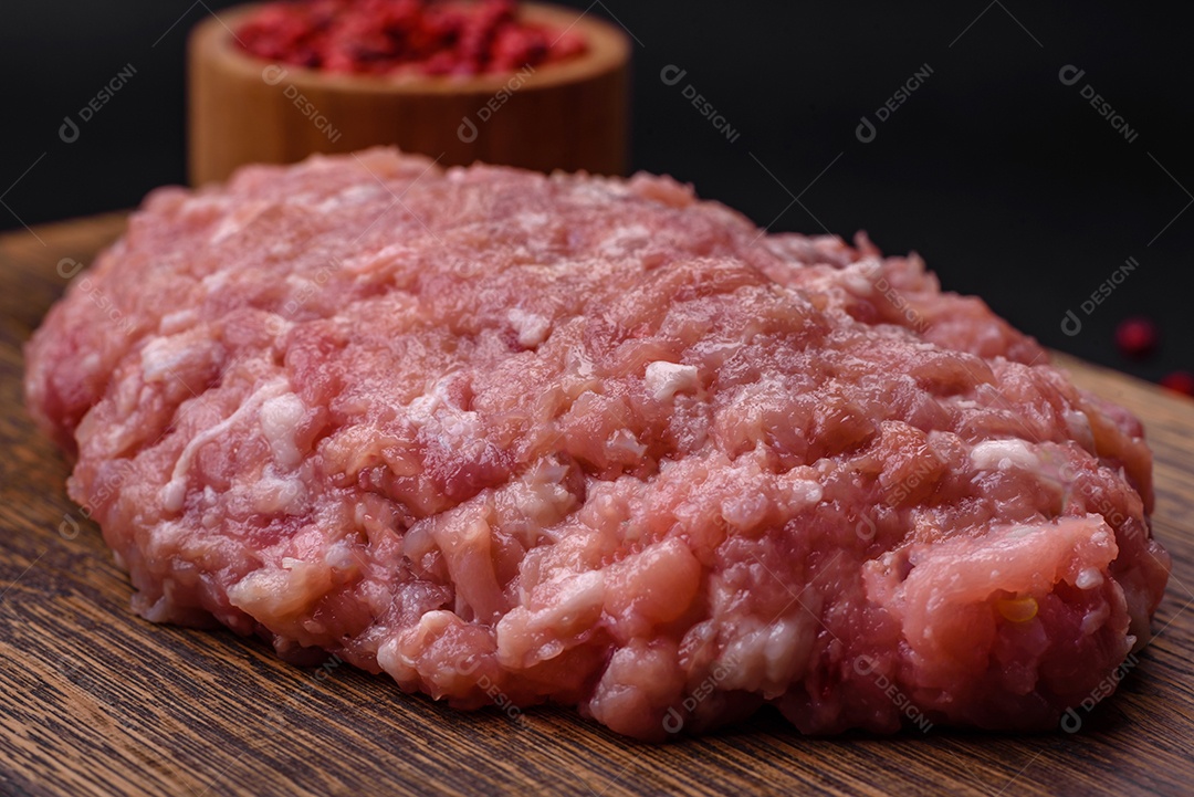 Almôndegas cruas de carne picada, carne de porco ou frango com sal, especiarias e ervas sobre um fundo escuro de concreto