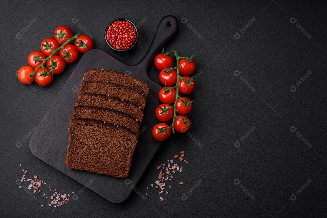 Delicioso pão integral fresco com grãos e sementes cortados em uma tábua de madeira sobre um fundo escuro de concreto