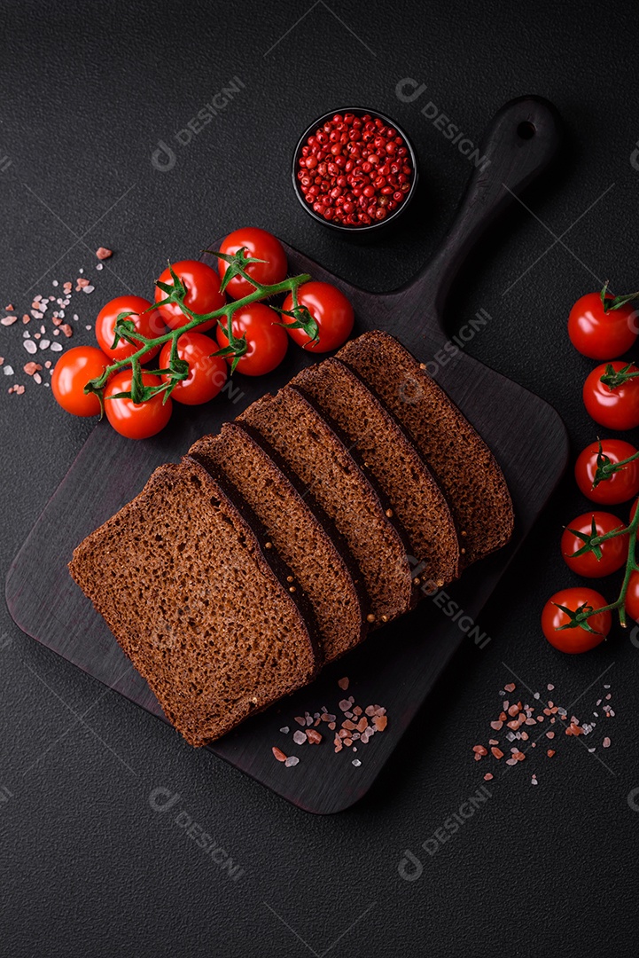 Delicioso pão integral fresco com grãos e sementes cortados em uma tábua de madeira sobre um fundo escuro de concreto