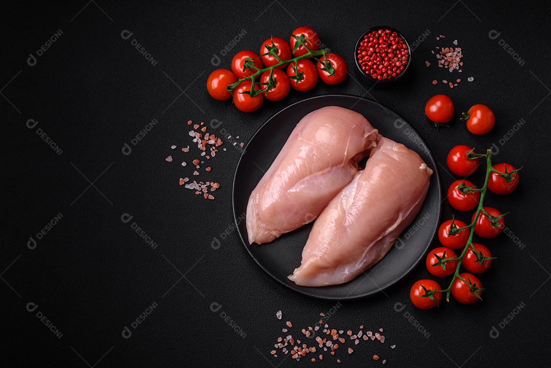 Pedaços de frango cru ou filé de peru com sal, especiarias e ervas sobre um fundo escuro de concreto