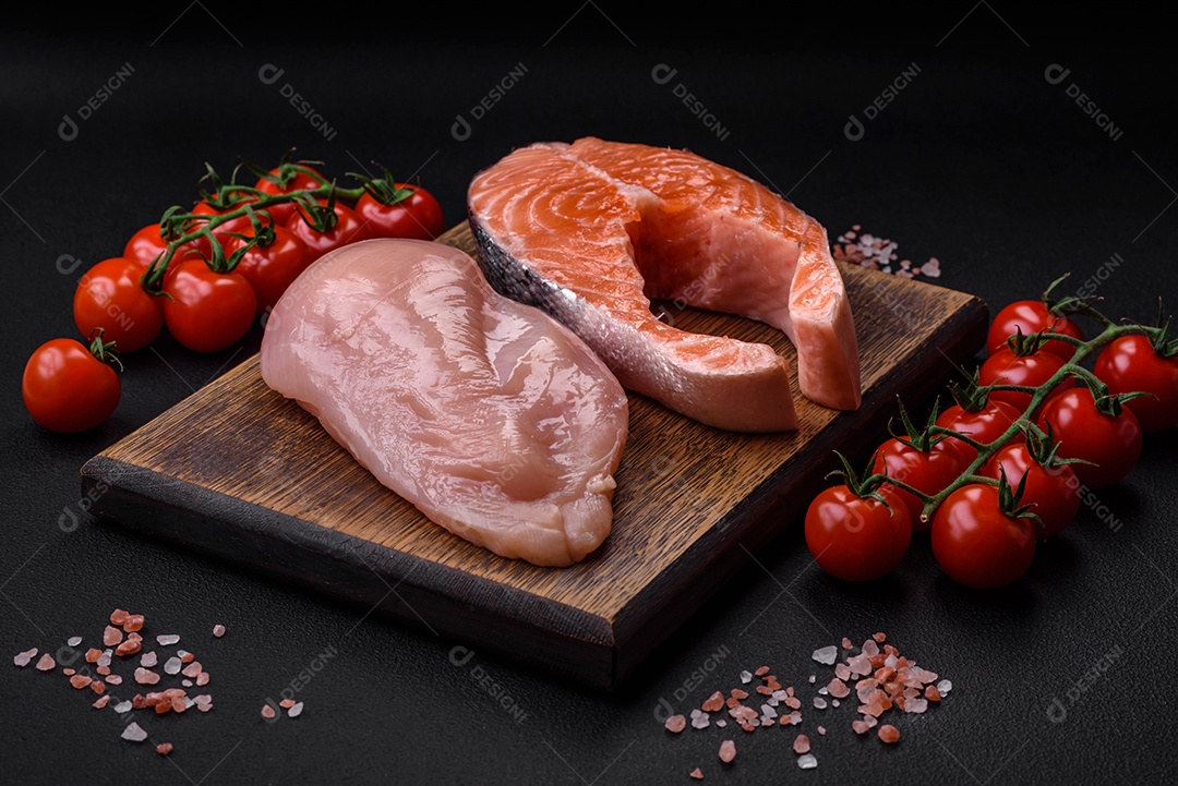 Filé de frango ou peru e filé de salmão com especiarias e ervas sobre um fundo escuro de concreto