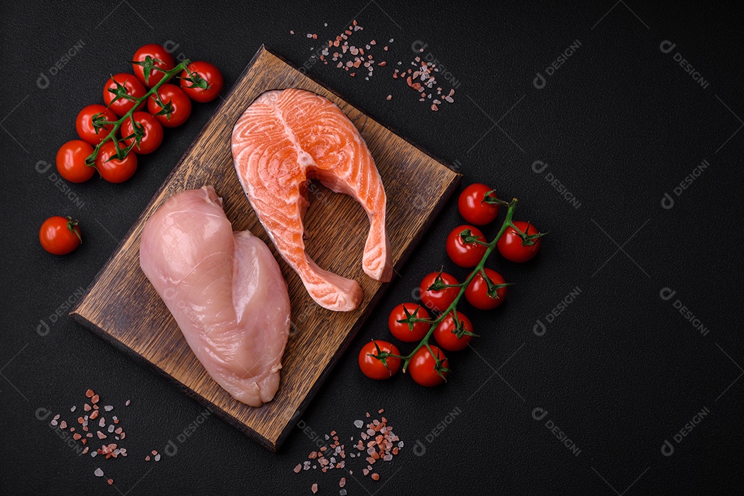 Filé de frango ou peru e filé de salmão com especiarias e ervas sobre um fundo escuro de concreto