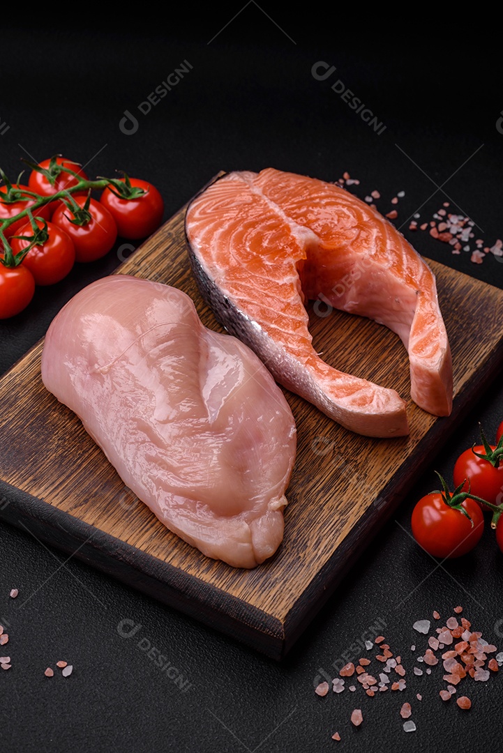 Filé de frango ou peru e filé de salmão com especiarias e ervas sobre um fundo escuro de concreto