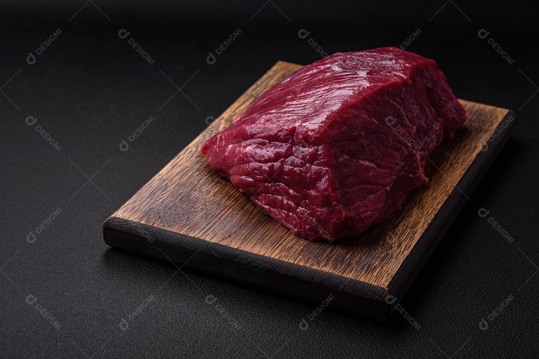 Carne de porco crua com osso ou costela cortada com sal, especiarias e ervas sobre um fundo escuro de concreto