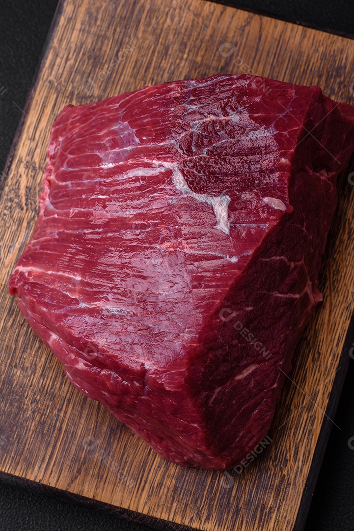 Carne de porco crua com osso ou costela cortada com sal, especiarias e ervas sobre um fundo escuro de concreto