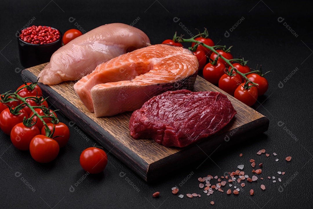 Filé de frango ou peru, bife cru e bife de salmão com especiarias e ervas sobre um fundo escuro de concreto