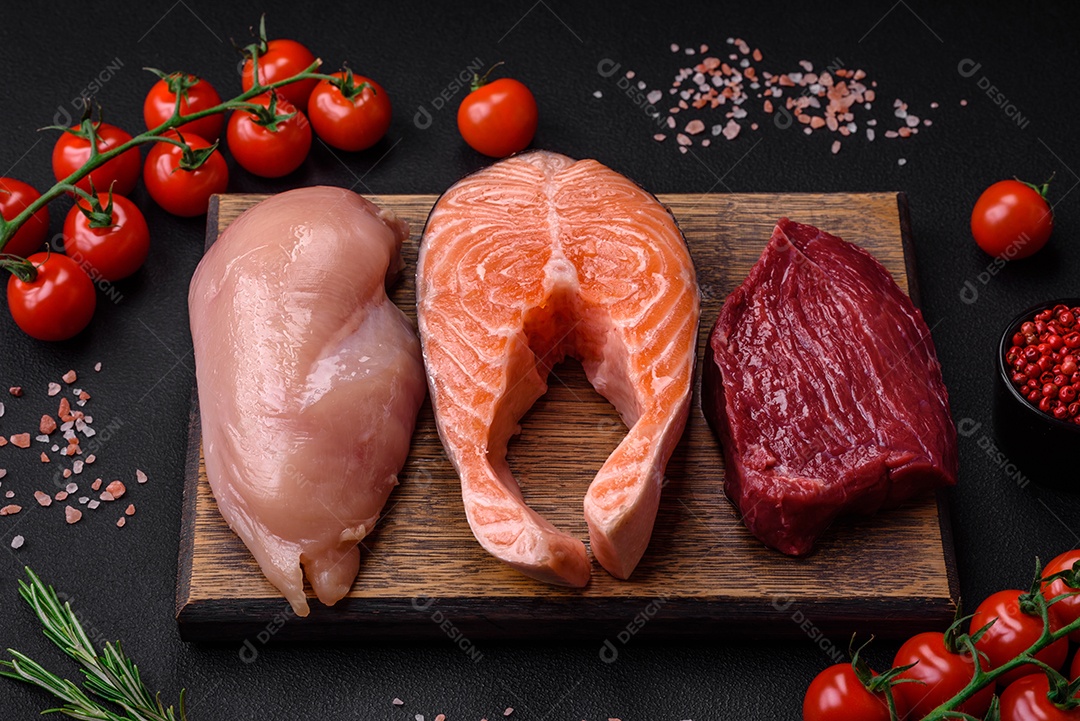 Filé de frango ou peru, bife cru e bife de salmão com especiarias e ervas sobre um fundo escuro de concreto