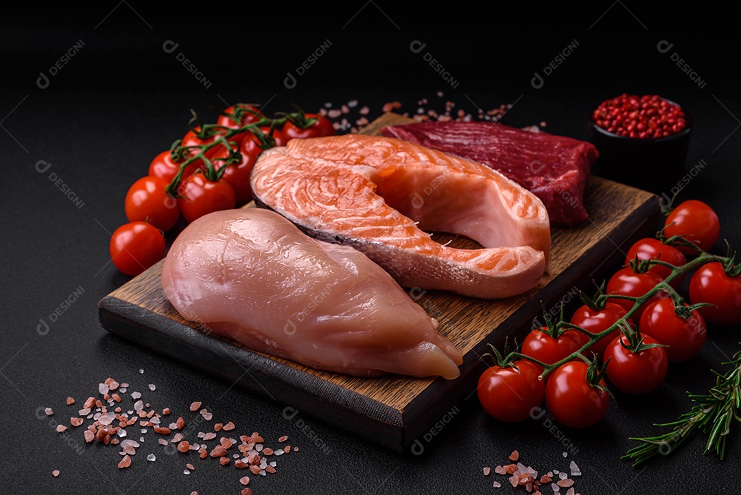 Filé de frango ou peru, bife cru e bife de salmão com especiarias e ervas sobre um fundo escuro de concreto