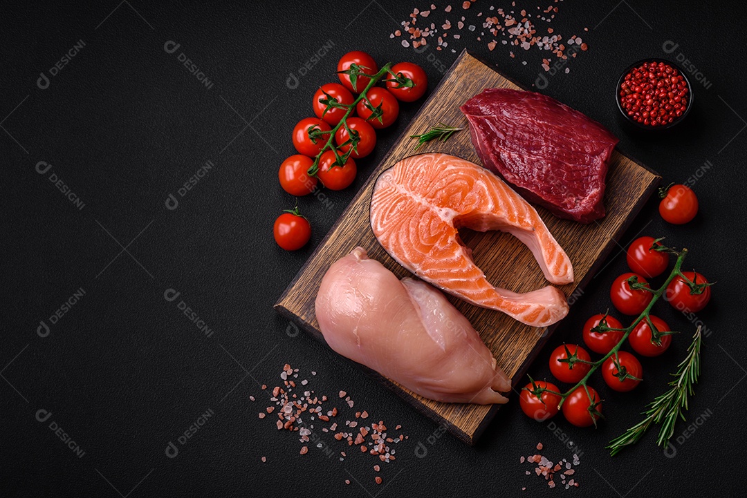 Filé de frango ou peru, bife cru e bife de salmão com especiarias e ervas sobre um fundo escuro de concreto
