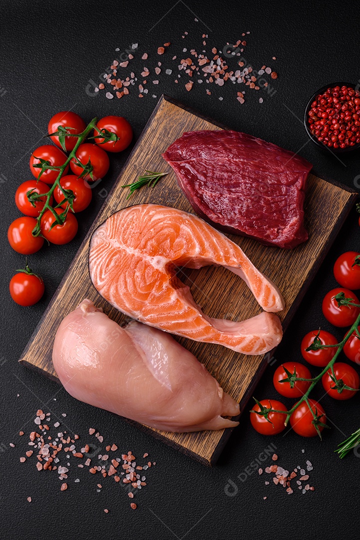 Filé de frango ou peru, bife cru e bife de salmão com especiarias e ervas sobre um fundo escuro de concreto