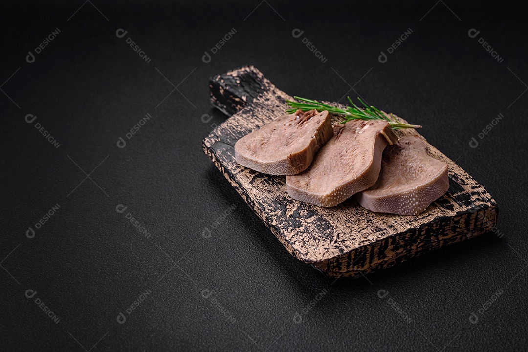 Deliciosa língua de boi cozida cortada com legumes e especiarias em um fundo escuro de concreto