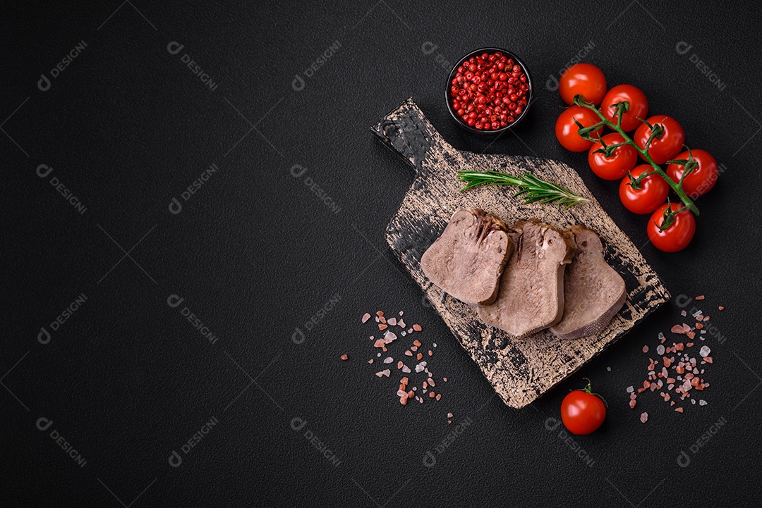 Deliciosa língua de boi cozida cortada com legumes e especiarias em um fundo escuro de concreto
