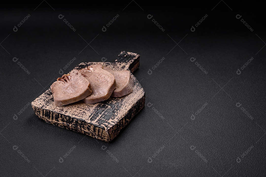 Deliciosa língua de boi cozida cortada com legumes e especiarias em um fundo escuro de concreto