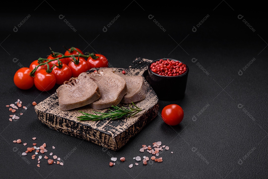 Deliciosa língua de boi cozida cortada com legumes e especiarias em um fundo escuro de concreto