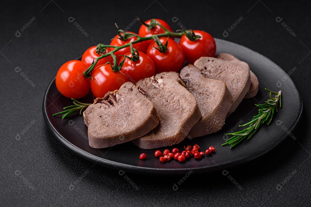 Deliciosa língua de boi cozida cortada com legumes e especiarias em um fundo escuro de concreto
