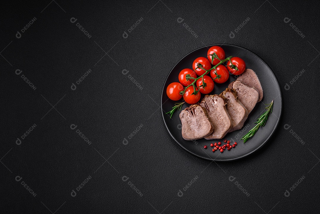 Deliciosa língua de boi cozida cortada com legumes e especiarias em um fundo escuro de concreto