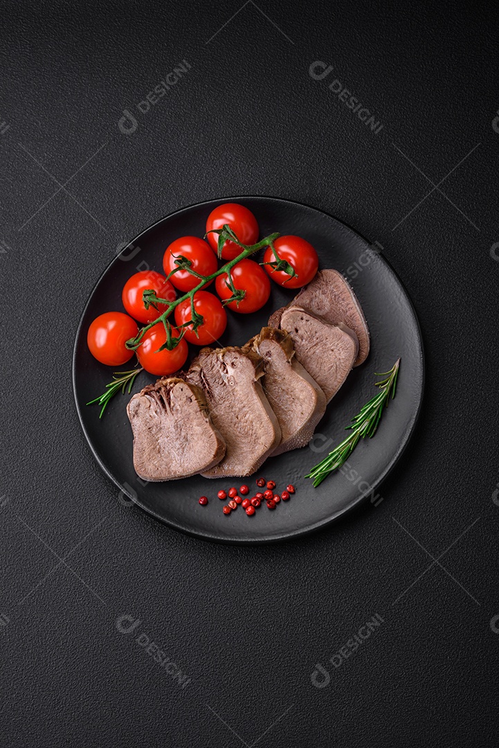 Deliciosa língua de boi cozida cortada com legumes e especiarias em um fundo escuro de concreto
