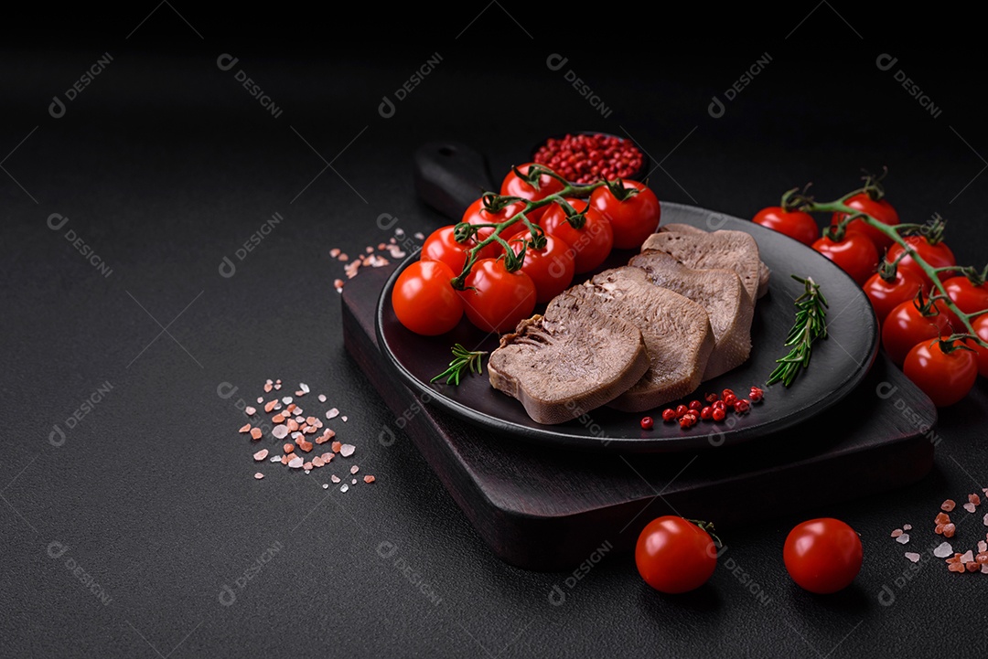 Deliciosa língua de boi cozida cortada com legumes e especiarias em um fundo escuro de concreto