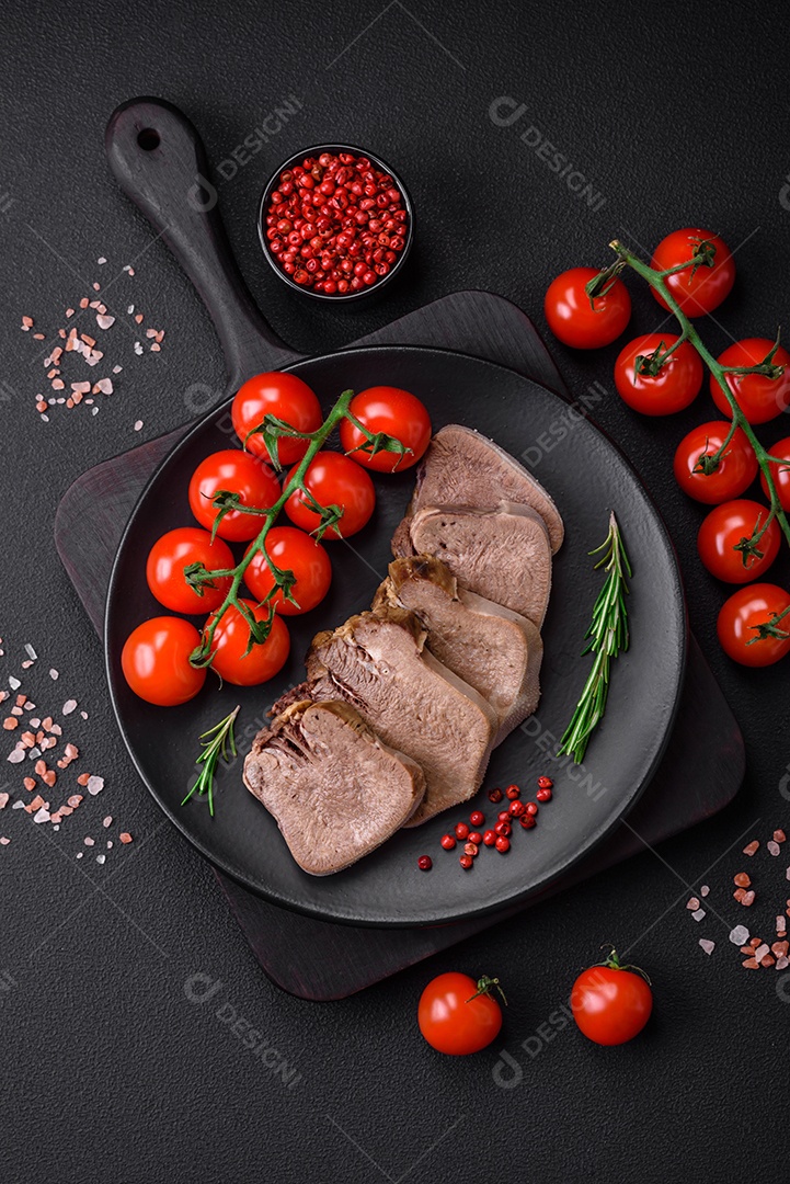 Deliciosa língua de boi cozida cortada com legumes e especiarias em um fundo escuro de concreto