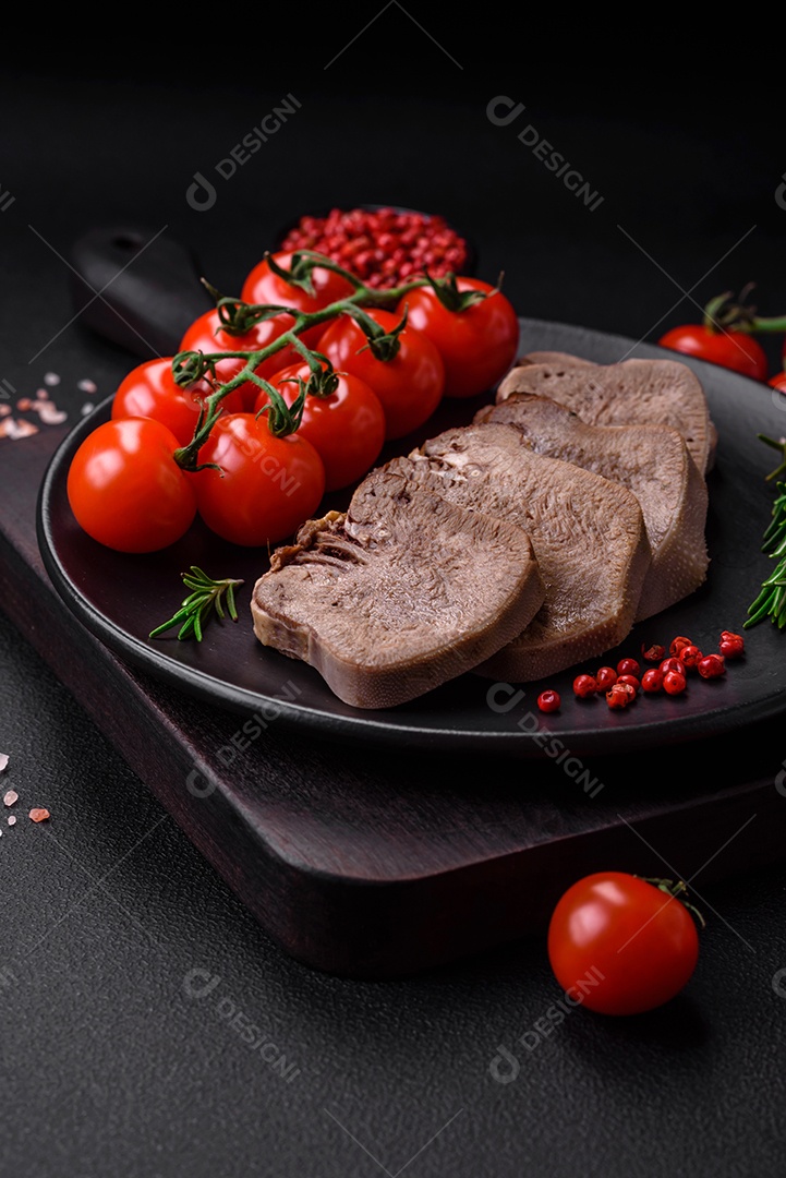 Deliciosa língua de boi cozida cortada com legumes e especiarias em um fundo escuro de concreto
